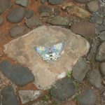 Stepping stone dengan ornamen keramik motif kupu-kupu.