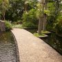 Jalur pejalan kaki menggunakan koral sikat tanpa motif berwarna terang di atas kolam.