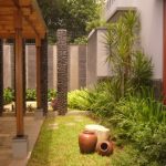 Pergola di atas carport rumah dengan material kayu.